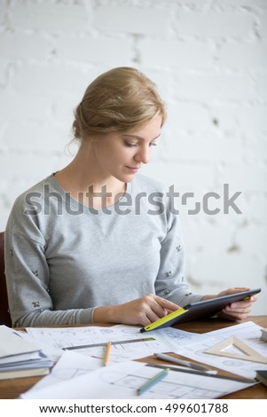 Portrait of an attractive woman working with a tablet sitting at the desk, lifestyle. Education concept photo, vertical