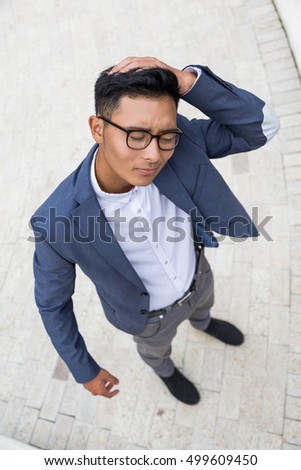 Asian businessman in elegant suit is having a headache in the street. Concept of overworking and stressful environment.