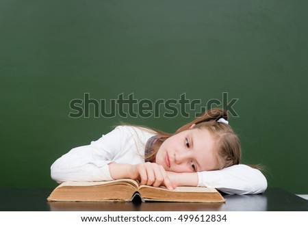 Tired girl reading a book in classroom