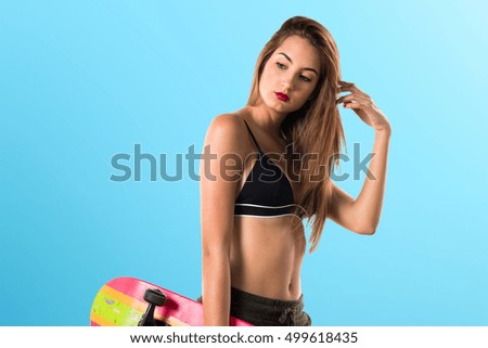 Pretty girl holding a skate on blue background