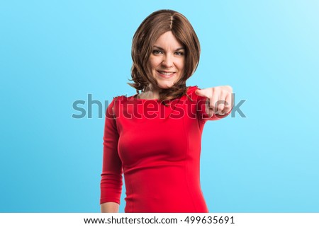 Brunette woman pointing to the front on blue backgound