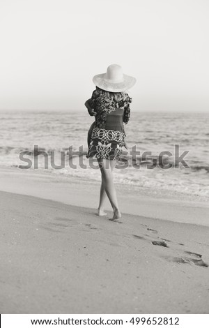 Black and white back side view of mother carrying child walking on sandy beach sunset outdoors background
