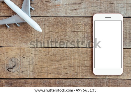 phone and airplane toy on wood table transport business concept top view, mock up smartphone blank screen