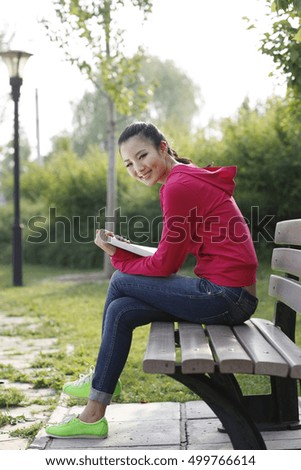 	Young woman reading a Book outdoors 	
