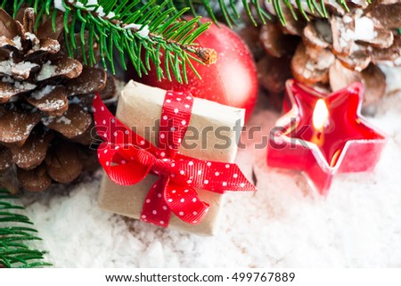 Christmas gift box with a red polka dots bow and ornaments ,fir and pine cones in the snow