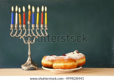 Image of jewish holiday Hanukkah with menorah (traditional Candelabra) and donuts