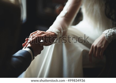 happy groom holds hand his young bride