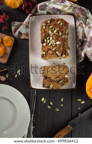 Dessert on Halloween. Homemade delicious cake with a pumpkin and dried apricots. Served on a wooden table with a plate, knife and fork. Vertical image. Top view. View from above
