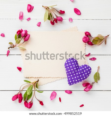 Old empty photo for the inside and frame of pink apple flowers and heart on white wooden background. Flat lay, top view.