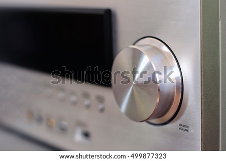 The shiny master volume knob of a home-theater amplifier. With depth of field.