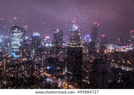 Warsaw, Poland city center through glass window on rainy day. Blurred night lights of the city abstract background.