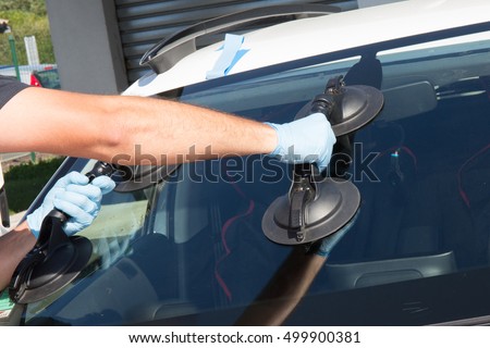 Mechanic man is changing windscrenn on a car Royalty-Free Stock Photo #499900381