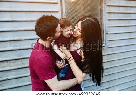 young beautiful family with child posing on the building background