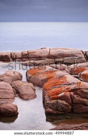 Tranquil Freycinet scene of sea and orange lichen rocks