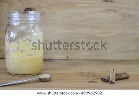 pumpkin puree in jar on wooden background with cinnamon sticks and measuring spoon baking scene