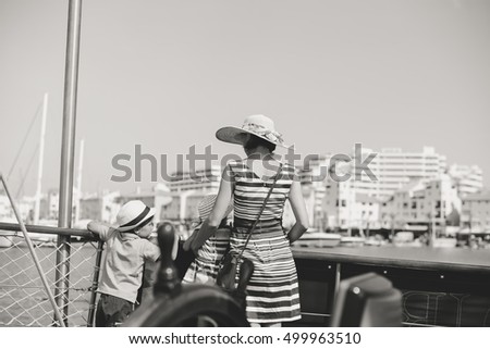 Closeup on steering wheel of sailing ship and back view of mother with kids. Sunny sky outdoors background. Book cover idea design