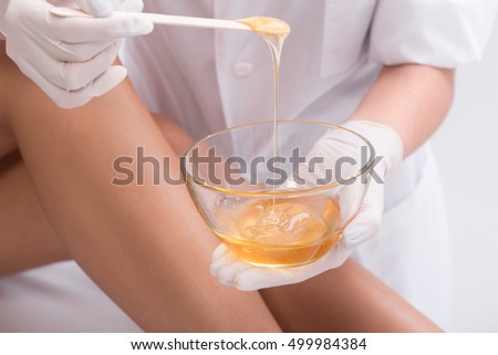 Young woman waxing her lower leg Royalty-Free Stock Photo #499984384