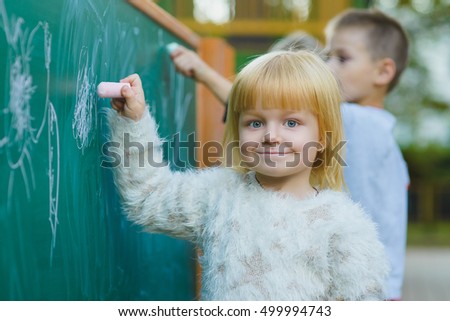 Cute children drawing with chalk on blackboard outdoor