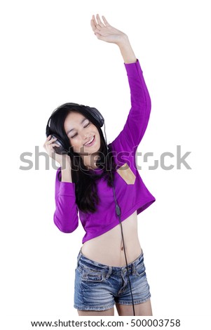Happy young woman listen music while dancing in studio
