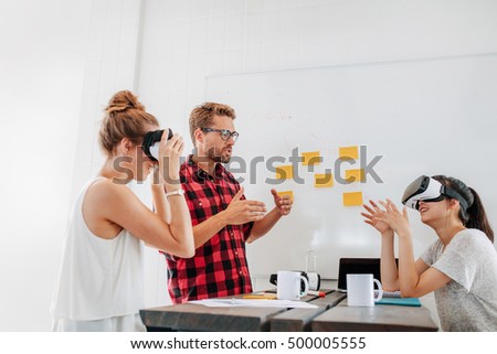 Team of developers working with virtual reality glasses during a business meeting. Young man with female colleagues brainstorming on augmented reality technology devices.