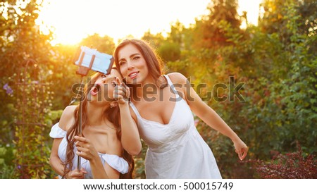 Two cute sisters make fun selfie. Girls fooled. They are singing. Family fun.