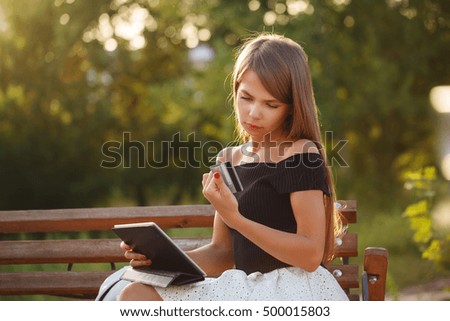 Cute girl holding a tablet pc and credit card. Payment for online purchases.