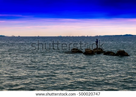 Silhouette of Fisherman with sunset background along Bang-sean Beach Chonburi Thailand
