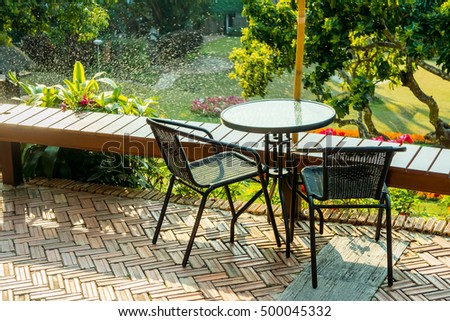 Modern round table and wicker chairs with sunshine. They are on a terrace or patio.