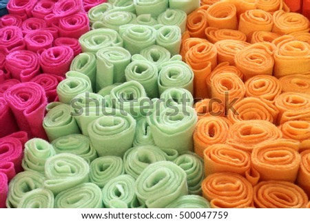 Many rolls of colored felt for sale in the market stall of fabrics