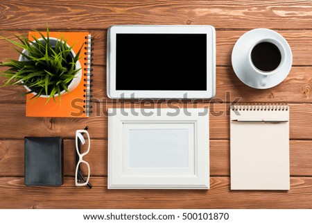 Still life photo of tablet notepad coffee glasses and other stuff on wooden table