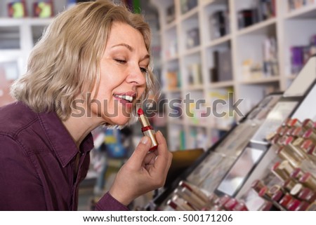 mature woman choosing lip plumper on display and smiling