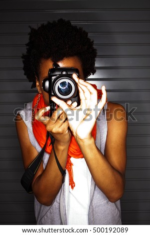 Woman holding a DSLR camera taking photographs.

