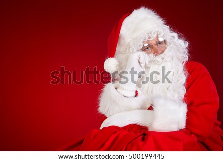 Santa Claus with huge bag full of christmas presents isolated on red background