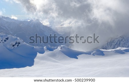 Snow forms formed by a strong wind in the mountains in sunny day. Sun. snow and wind  converted a solid deep snow into the scenic natural pattern like beautiful wave of the frozen sea.

