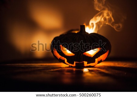 Glowing Halloween pumpkin jack o' lantern with devil face on the wall. (low key)