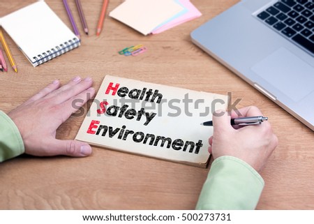 Hand writing Health Safety Environment. Office desk with a laptop and stationery