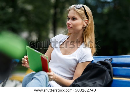 Dreamy girl with tablet in their hands sitting on bench