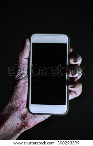 closeup of a scary and bloody hand holding a smartphone with a black blank space in its screen, against a black background