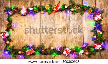 Christmas colored lights with fir decoration placed on wood. Copyspace for text