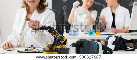 Mature scientist and two young students working in a laboratory, panorama