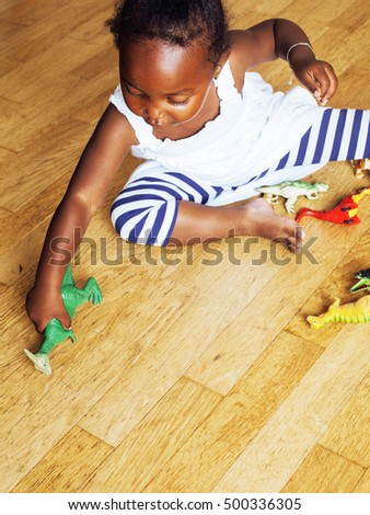 little cute african american girl playing with animal toys at ho