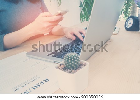 Office table with resume information and woman's hand hold smartphone, tablet, cell phone and search job, Shopping online, Office place on outdoor garden, Vintage effect style pictures.