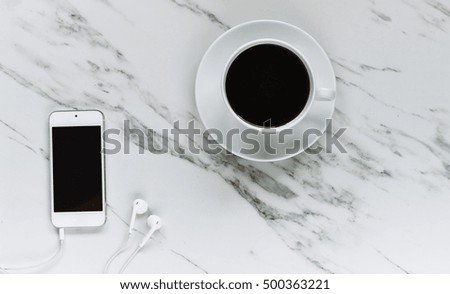 cup of coffee and phone with headphone on marble background. top view