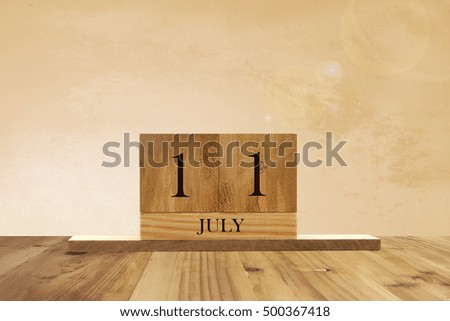 Cube shape calendar for July 11 on wooden surface with empty space for text.