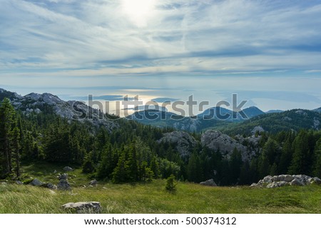 View of the Adriatic sea from Sjeverni Velebit national park, Croatia. Large mountain meadow with mountain tops. Islands and sea in background.