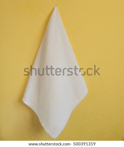 White Spa towel hanging on a yellow wall Royalty-Free Stock Photo #500391319