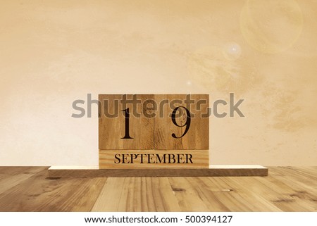 Cube shape calendar for September 19 on wooden surface with empty space for text.