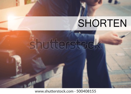Hand writing SHORTEN with the young business man on background. Business concept. Stock Photo.