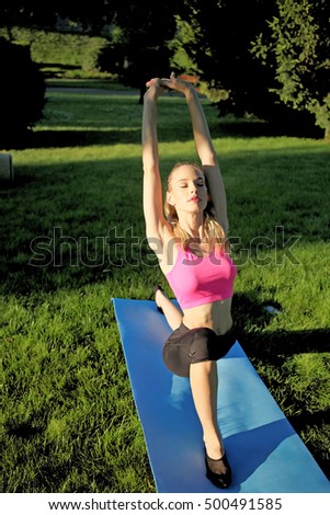 Young girl doing yoga in the park. Muscled fitness girl is working out in the park. Woman exercising on playground in park.