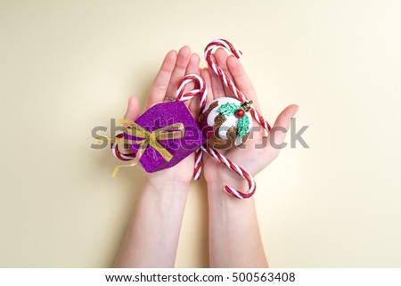 Christmas decorations in the hands of a girl. Woman holding  Happy Holidays table bright white yellow background letters xmas 